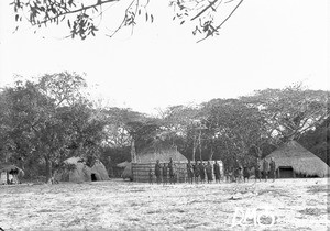 Group of African people standing in front of huts, Makulane, Mozambique, 1910