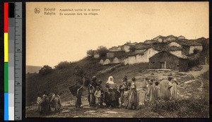 Missionary sister and villagers standing before a hillside village, Algeria, ca.1920-1940