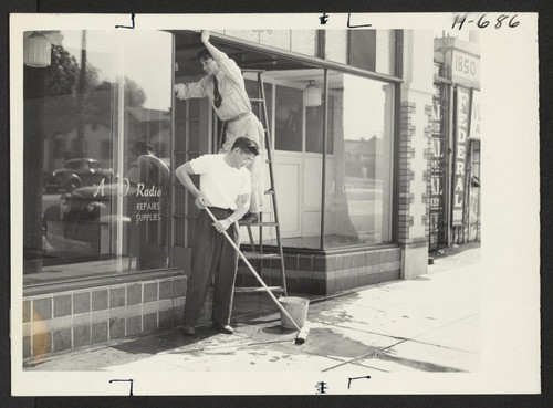 Jiro Oishi and Satoru Akutagawa (on the ladder), setting up their new shop, the A-O Radio Service, at 1856 E