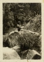 Woman seated on rock, wearing bathing suit