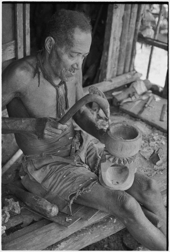Carving: M'lapokala uses a decorated adze to carve a wooden bowl with stand, probably for tourist trade