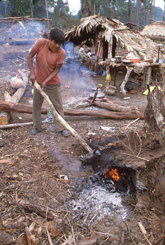 Guatemalan refugee pokes a fire outside at a refugee camp, Chajul, ca. 1983