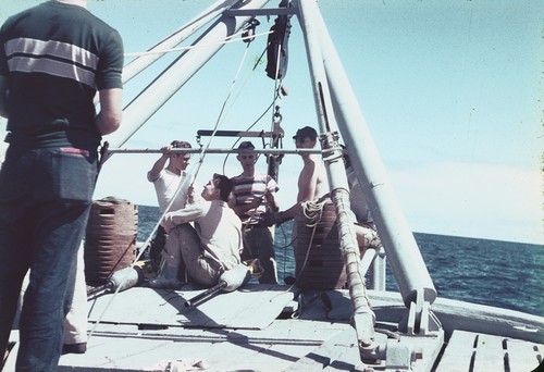 Jeffery D. Frautschy (center in stripped T-shirt) with other unidentified men near the A-frame on the fantail of R/V Horizon during the MidPac expedition. 1950