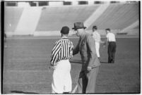 Football coach speaking to a referee on the Coliseum field, Los Angeles, 1937