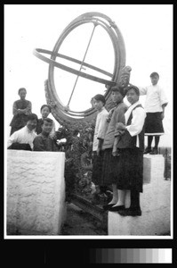 Viewing astronomical instrument on Yenching University group outing to city wall, Beijing, China, ca.1920-1930