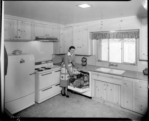 Woman loading dishwasher in electric kitchen
