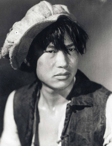 Movie head shot of Chinese man wearing hat and black vest