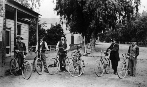 Five men and a young boy with their bicycles in downtown Tustin
