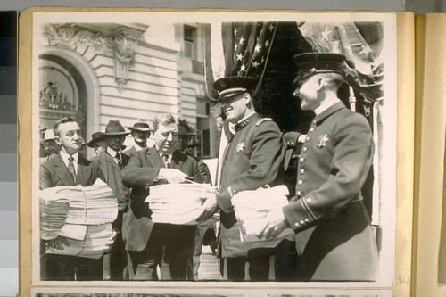 Two photos of Mr. J.S. Dunnigan, Clerk to the Board of Supervisors, receiving the S.F. [San Francisco] Police Petition for an increase of salary at the New City Hall to be voted on at the Nov. election, 1920