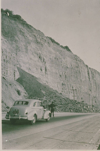 Police officer standing at the site of a landslide on Pacific Coast Highway