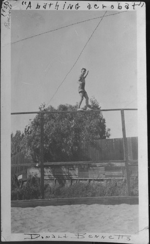 Young man, Donald Bennetts, walking on tall fence at Riverside