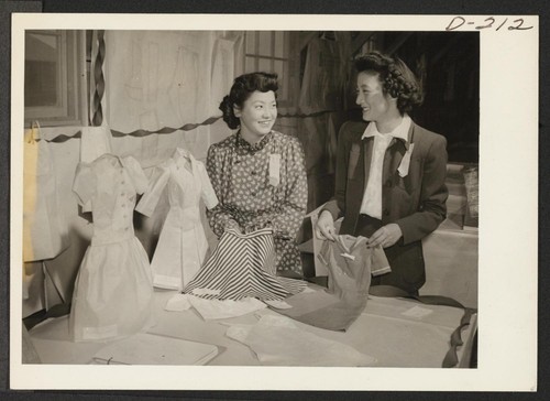 These attractive young evacuees show the garments made by the pattern drafting class in Block 1308. (L to R) Mary Arima, Mrs. Alice Tsukuno. Photographer: Stewart, Francis Newell, California