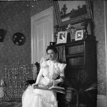 Interior view of a woman seated with a book on her lap. Possibly Ellen Henry of Orangevale