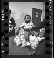 Infant, Dedrionne Stovall, sitting on bags of pennies as part of HUD housing demonstration in Los Angeles, Calif., 1972