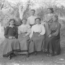Exterior view of seven women standing in a wooded area