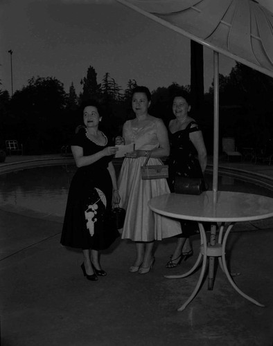 Women stand next to a pool