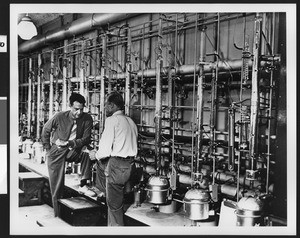 Two men conferring inside an unidentified factory, ca.1950