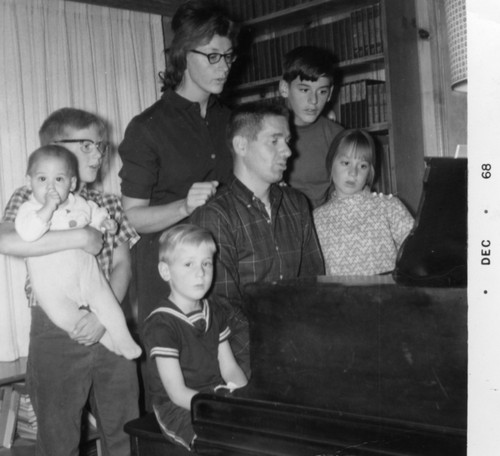 Charles D. Keeling family around the piano (left to right: baby Paul, Ralph, Eric (seated), Louise and Charles D., Andrew and Emily)