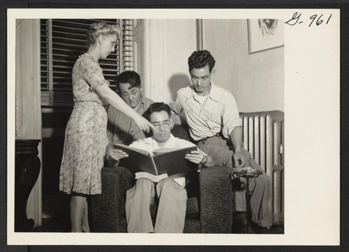 Mrs. Eldon Burke, director of the Brooklyn Hostel for Japanese Americans, shows an album of clippings to Robert Kazahaya, Kohay