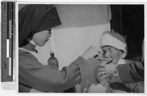 Sister Margaret, MM, washes an old woman's cancerous eye, Yeng You, Korea, ca. 1930-1950