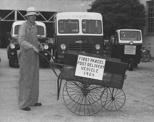 May Festival participant Wayne Sherrill with the first Pacel Post push-cart delivery vehicle, Orange, California, 1954