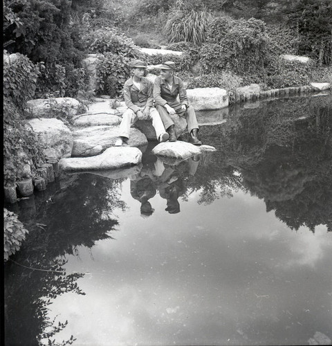 Soldier and young man sitting by pond