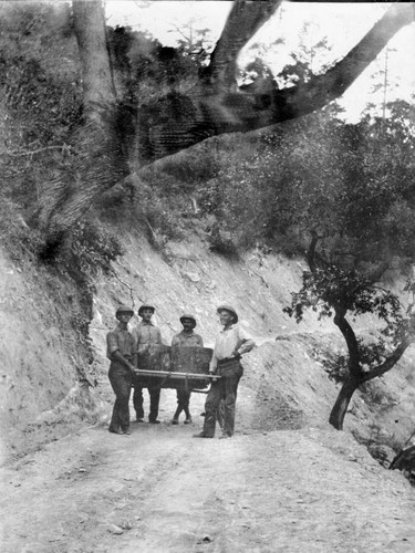 Railroad construction men holding boulder in Feather River Canyon