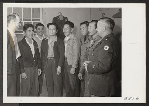 Ray D. Johnston, left, center director, and Captain John A. Holbrook, chief of an army recruiting team, discuss army with a group of volunteers and Sergeant Isamu Adachi, at the Rohwer Relocation Center. Photographer: Parker, Tom McGehee, Arkansas