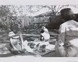 Mary, Bonnie and Bill Alwes with Michael McGregor in the backyard of an unidentified house, Santa Rosa, California, 1957