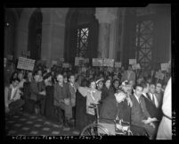 Protesters with signs in gallery of city council chamber during hearing on Chavez Ravine in Los Angeles, Calif., 1951