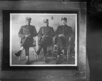 Three firemen seated with legs crossed