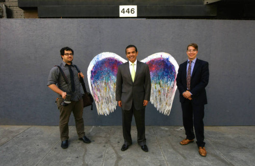 Antonio Villaraigosa and two unidentified men posing in front of a mural depicting angel wings