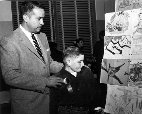 Upland Photograph Public Services; Upland Police Department: Officer with student at an art show