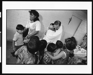 Priest hugging child, Dolores, Los Angeles, 1996