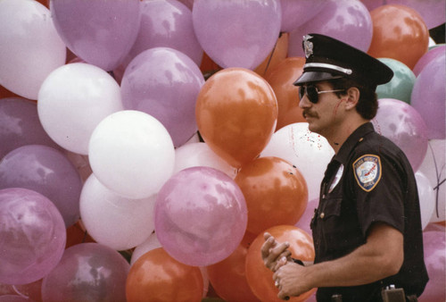 Police officer next to balloons at Olympic torch relay on July 21, 1984, Santa Monica, Calif
