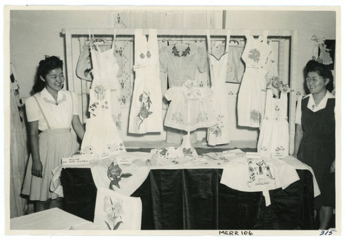 Photograph of two girls standing in front of a display of stencil decorated items