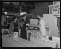 Woman serves samples behind a display at the Food and Household Show, Los Angeles, 1935