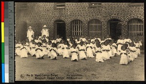 Missionary sisters standing outdoors among rows of kneeling young women, Congo, ca.1920-1940