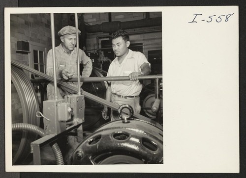 Archie Wiels, engineer at the Becker Cold Storage Plant, confers with Paul Shimada, Labor Supervisor, in the refrigeration room. Mr. Shimada is formerly from the Rohwer Relocation Center and Lodi, California. Photographer: Iwasaki, Hikaru Decatur, Michigan