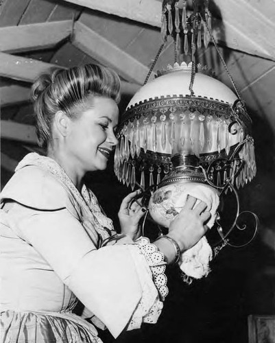 Woman cleaning chandelier in the Avila Adobe