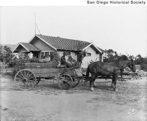 A man driving a wagon pulled by two horses
