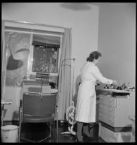 Aulanko Military Hospital. Doctors. [Woman dentist Dr. Kivimaki, wife of surgeon Dr. Juuso Kivimaki, working in converted hotel room, using a barber's chair for patients]