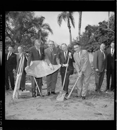 Group of men in suits breaking ground on a project