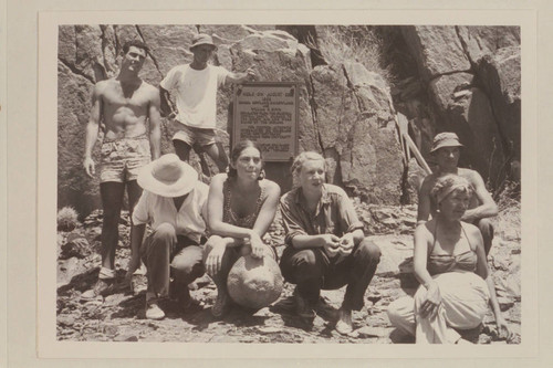 Part of Nevills party posed in front of plaque at Separation Canyon.Garth Marston at left;Norm Nevills with hand on plaque.Marie Saalfrank ducks her head.Anne and Zoe Desloge crouch at front center.Kent Frost and Margaret Marston at right