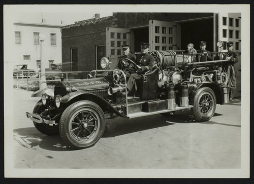 Four unidentified personnel on a 1923 Seagrave Aerial (?)