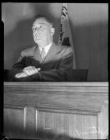 Board of Education member Stewart O. Mertz sits behind a podium, Los Angeles, 1935