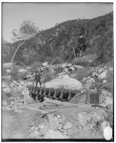 An unknown man standing on an unknown "flume" structure in an unknown canyon