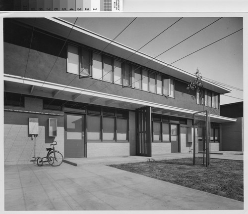 Photograph of a tricycle parked in front of a public housing unit (Channel Heights ?) in Los Angeles, California