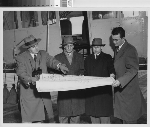 Photograph of Housing Authority officials and others standing in front of a blimp examining a field study