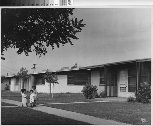 Photograph of three young children outside units at Hacienda Village